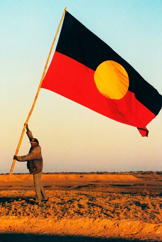 person setting up Australian aboriginal flag 